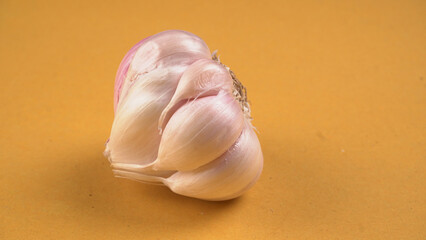 Organic Garlic. Fresh Garlic Cloves and Garlic bulb in wooden basket on yellow background with Pile of garlic or spice. Concept of spices for healthy cooking.