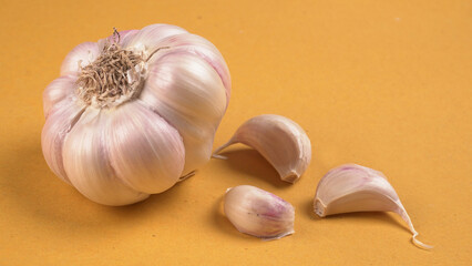Organic Garlic. Fresh Garlic Cloves and Garlic bulb in wooden basket on yellow background with Pile of garlic or spice. Concept of spices for healthy cooking.