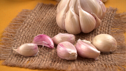 Organic Garlic. Fresh Garlic Cloves and Garlic bulb in wooden basket on yellow background with Pile of garlic or spice. Concept of spices for healthy cooking.
