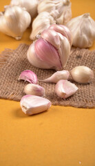 Organic Garlic. Fresh Garlic Cloves and Garlic bulb in wooden basket on yellow background with Pile of garlic or spice. Concept of spices for healthy cooking.