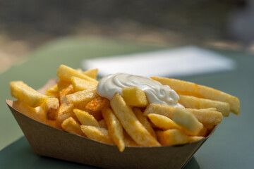 A tray of french fries with a white sauce on top. The fries are golden brown and appear to be crispy. The white sauce is drizzled over the fries, adding a creamy texture and flavor