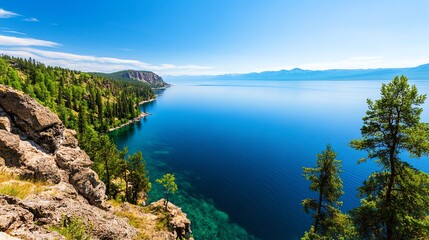 Fototapeta premium Stunning panoramic view of a crystal clear lake with forested hillsides and mountains in the distance.