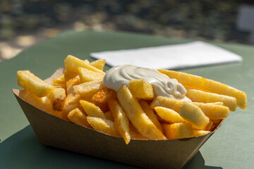 A basket of french fries with a white sauce on top. The fries are golden brown and crispy