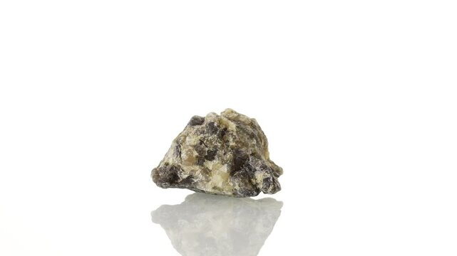 Cordierite mineral stone spinning in a circle on a white background