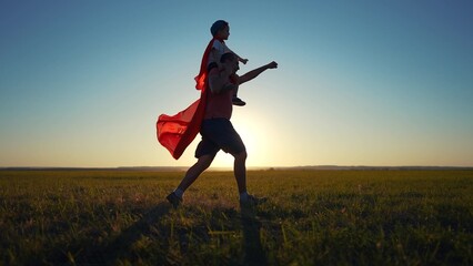 Father and son running superhero silhouette. Child family super concept. Silhouette of a superhero with his daddy and baby. Silhouette of superhero with father and son running grass on.