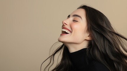 A young woman with long dark hair, laughing with joy. Her hair flows freely as she smiles, creating a dynamic and happy atmosphere against a neutral background.