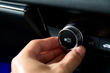 Fototapeta premium Close up hand turning the button to automatically adjust the air conditioning temperature in a modern car luxury interior 2024. Function control buttons in modern car.