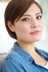 Asian woman, portrait and relax in house on sofa for leisure, peace and comfortable on weekend break. Female person, face and chill in living room on couch for wellbeing, self care or rest on day off