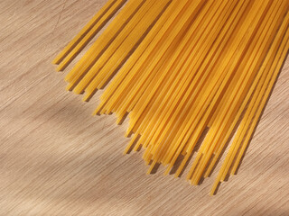 Dry Italian pasta lies on the table in the sun. Background, place for text. Making pasta. Wheat pasta. Traditional cuisine. Spaghetti close-up. The concept of carbohydrates in pasta.