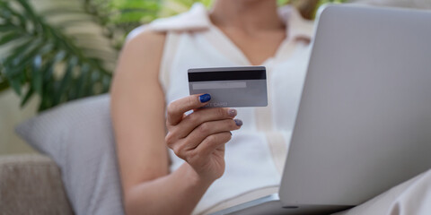 Asian woman in her 20s shopping online with credit card, concept of digital spending in modern technology