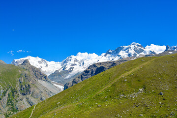 Swiss Alps peaks and ridges covered in snow in Summer. Stunning mountain landscape in Switzerland. Panoramic shot. Space for copy. 