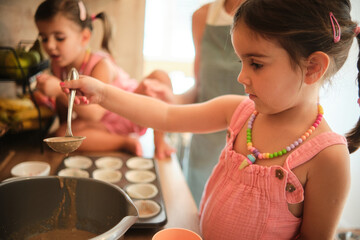 Little girl baking muffins in a cozy kitchen with family on a sunny afternoon