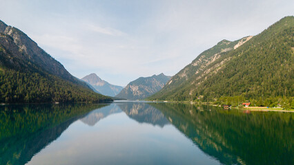 Fototapeta premium A tranquil morning at Plansee in Austria surrounded by majestic mountains and calm waters