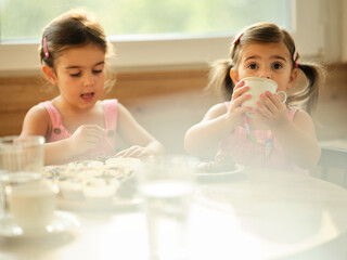 Two young girls enjoy a creative afternoon baking cupcakes together in a bright kitchen with large windows