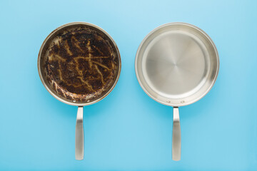 Dirty oily and clean stainless frying pans on light blue table background. Closeup. Pastel color....
