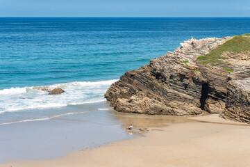 Man sitting on a chair on the beach of the cathedrals while relaxing and enjoying the sea, Galicia, Spain.