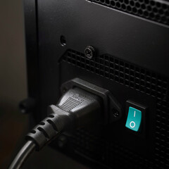 Modern computer AC power supply with connected power cable on dark background