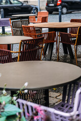 Outdoor cafe with empty tables and chairs, shaded patio, historic European architecture, cozy atmosphere, urban dining, street cafe.