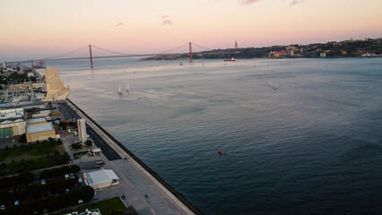 An aerial drone image of tagus river in Lisbon, Portugal, set against the serene backdrop of the Tagus River at sunset. Lisbon