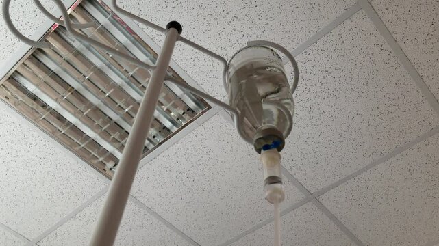 Intravenous infusion drops. Drip administration of saline solution during hospital treatment. Soft focus. During the procedure, the liquid is in the vial.