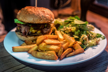 Delicious burger with beef patty, tomato sauce salad and French fries