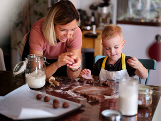 A mother and her young son enjoy a fun baking session making chocolate cookies together in their cozy kitchen