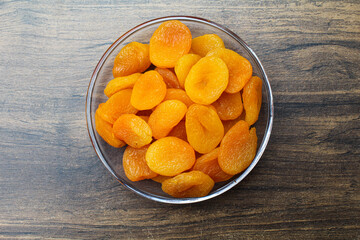 Dried Apricots in a plate on wooden background top view 