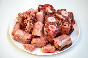 Raw beef oxtail on a round white plate in closeup.