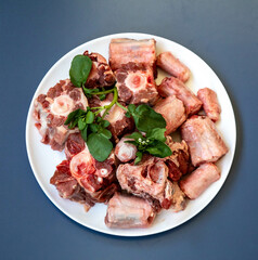 Raw beef oxtail on a round white plate in closeup.