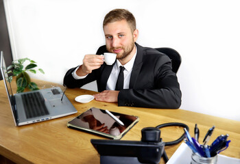 Naklejka premium Businessman in business office working and drinking coffee