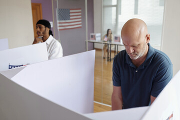 Men voting in booth in voting centre