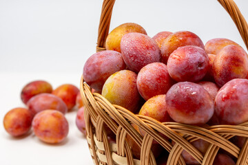 Beautiful ripe sweet plums in a basket isolated on white background. Close up.