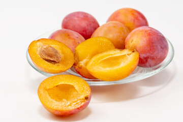 Halves of ripe sweet plums on a glass plate isolated on white background.