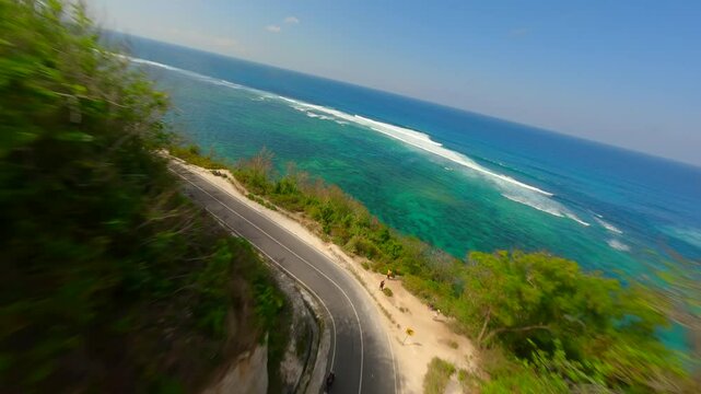 FPV flight over the road in limestone cliffs and the turquoise sea of Batu Barak beach in Bali, Indonesia