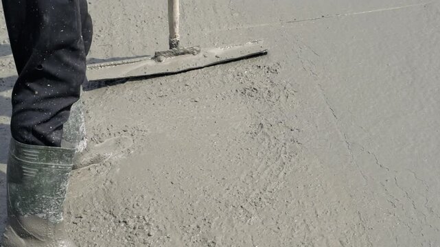 Close-up of leveling a wet concrete surface with a tool. Tamping and smoothing of a concrete slab.