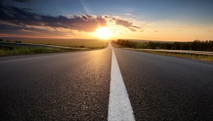 Naklejka premium black asphalt road and white dividing lines at sunset