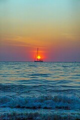 Fototapeta premium Picture of a sailing yacht on the sea in front of the setting sun in back light