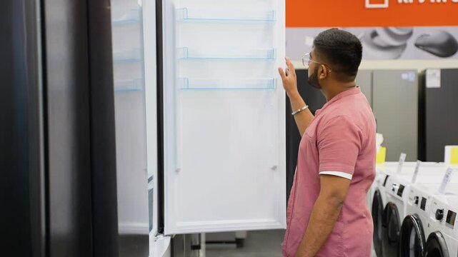 Indian man is viewing fridge in home appliances store
