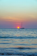 Picture of a sailing yacht on the sea in front of the setting sun in back light