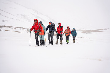 A group of people walking on the snowy mountains with their snowshoes on. Climbing the icy mountains