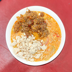 top view spicy curry noodle with beef topping on red background