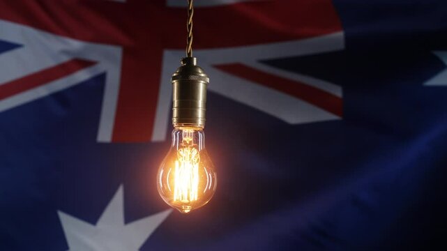 Flickering classic antique Edison Tungsten filament lamp on waving Australian flag background. Raising tariffs for electricity supply, bills, energy crisis in Australia. 