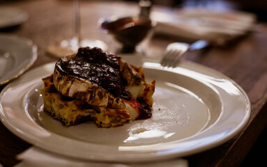 Golden fried camembert cheese sits atop crispy layers, drizzled with rich fruit jam, inviting indulgence for all.