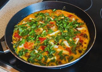 A vibrant omelette is being made, topped with fresh herbs and veggies for a delightful culinary experience.
