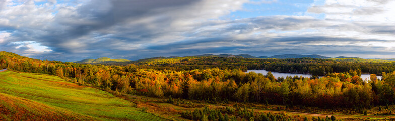 Fototapeta premium Panoramic photo autumn landscape with hilly mountains and lakes. Beautiful multicolored autumn trees and sky in the early morning.