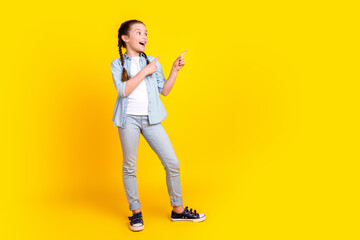 Photo of cheerful funny pretty girl wear trendy clothes recommend empty space isolated on yellow...