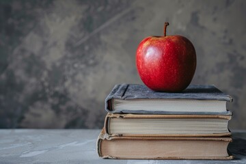 A neat stack of school textbooks with a shiny apple on top