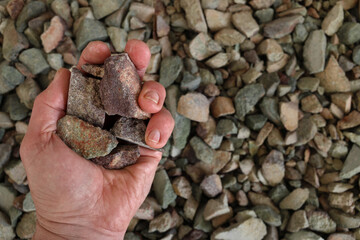 Rare earth (earths) ore, partially closed hand. Critical minerals, used for permanent magnets,...