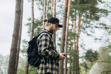 Male photographer with an analog camera in a pine forest in nature.