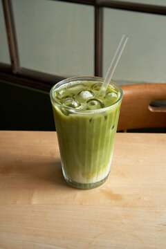 A matcha latte placed on a brown wooden table.